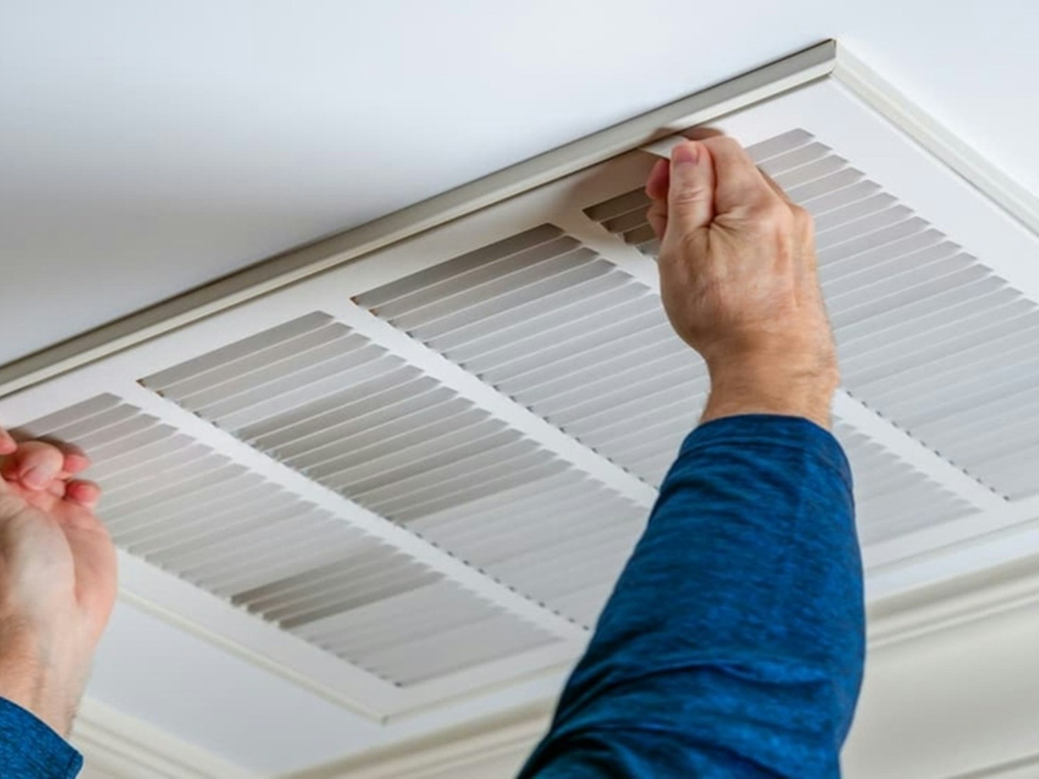 Technician removing a ceiling air vent grille for air quality testing